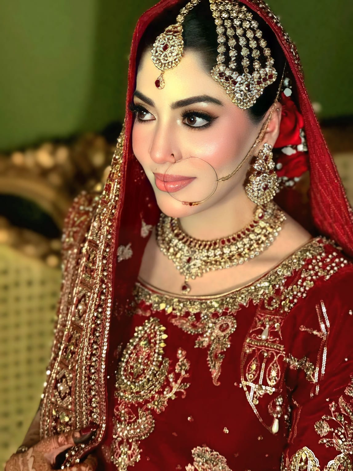 Close-up bridal portrait in red lehenga with heavy gold jewelry